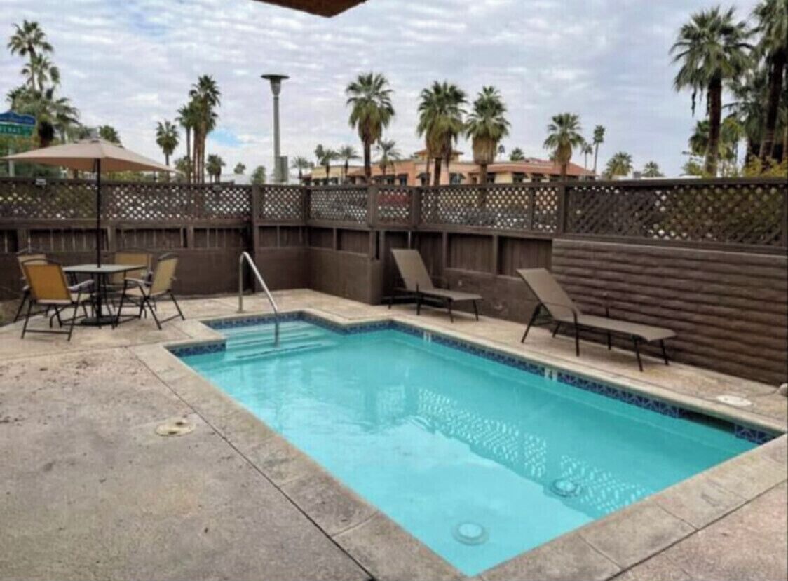 A pool area with lounge chairs and a fence.