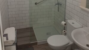 Une petite salle de bain moderne avec une douche à parois de verre, des toilettes blanches et un lavabo.