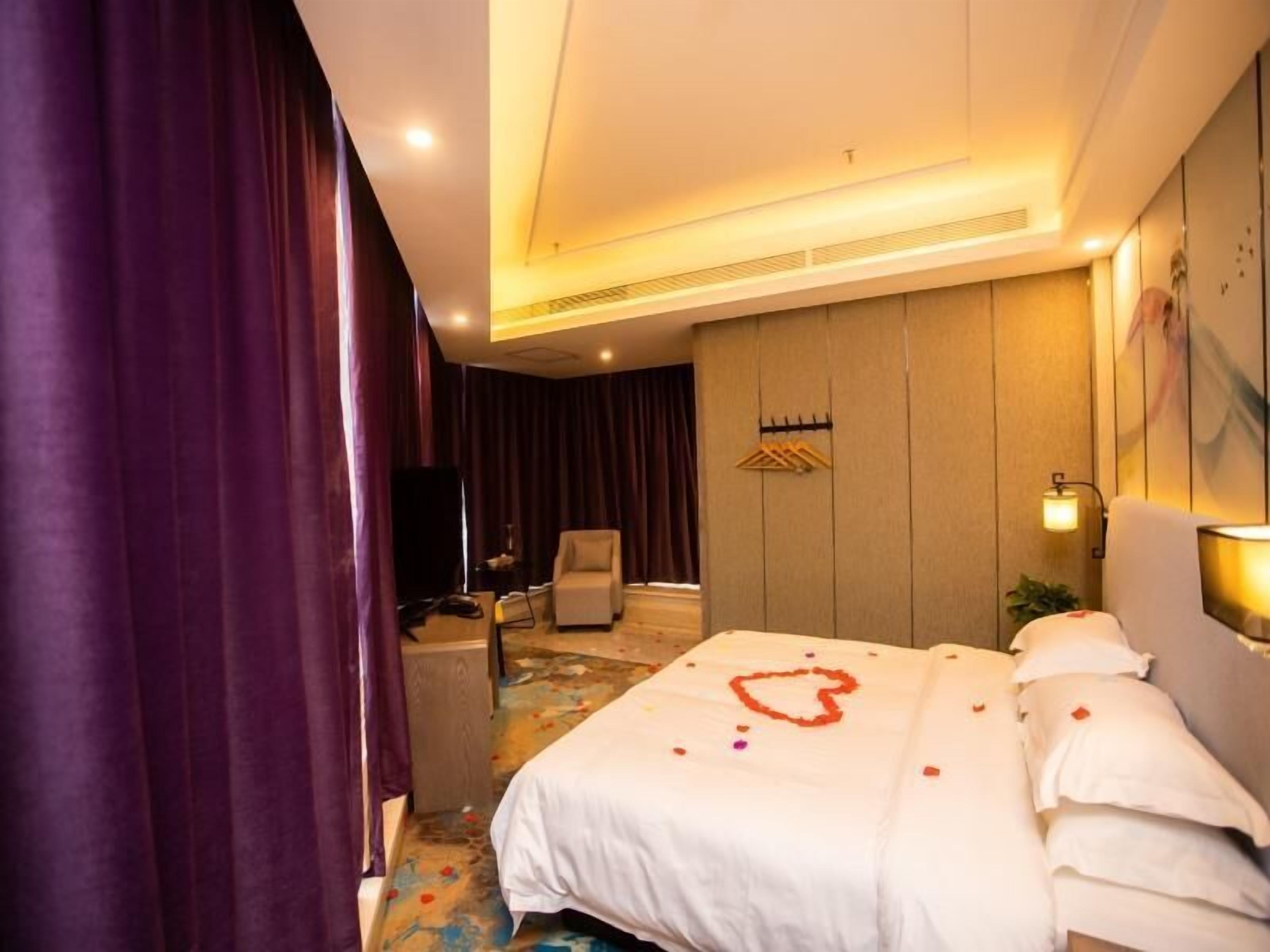A hotel room with a bed, a chair, a desk, and a television.