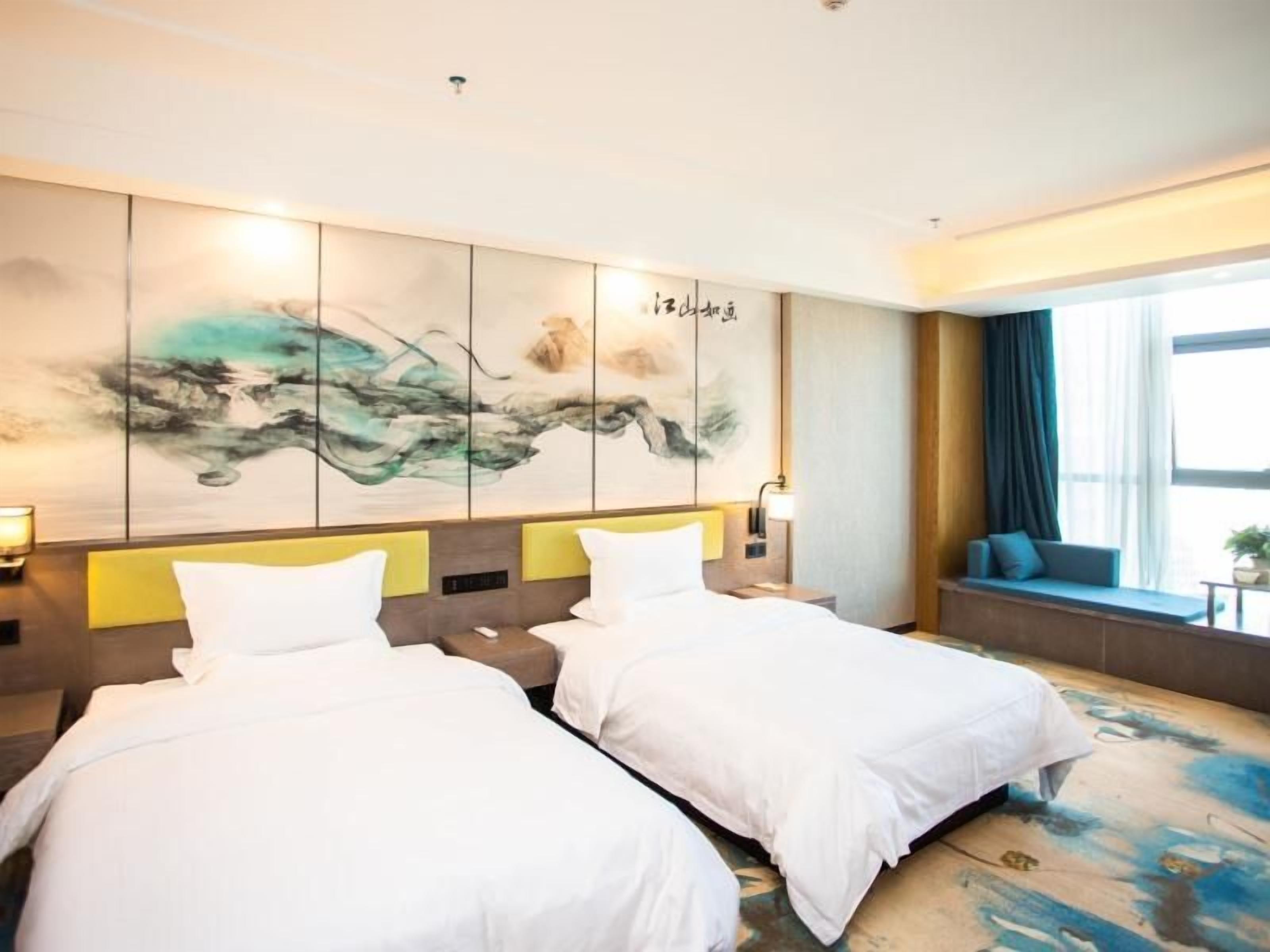 A hotel room with two beds, a large abstract painting on the wall, a window with curtains, and a seating area with a view.