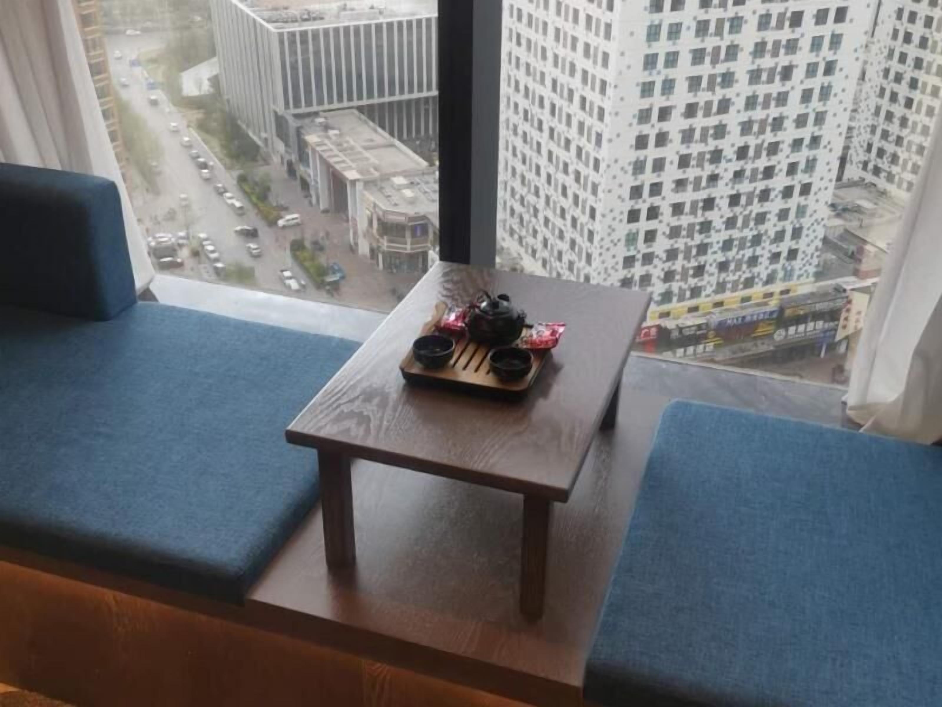 Ein Zimmer mit Holztisch und blau gepolsterten Sitzmöglichkeiten.