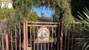 A gated entrance with a sign reading "Desert House Private" and a security warning.
