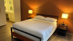A neatly made bed with white linens in a hotel room.