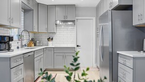 A modern kitchen with grey cabinets, a stainless steel refrigerator, and a coffee maker.