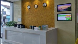 A reception desk with clocks, a digital screen, and a plant. - Shell Shanghai New International Expo Center Fanghua Road Metro Station Hotel (Shanghai)