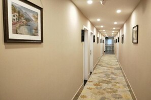 A hotel hallway with framed artwork on the walls, a patterned carpet, and doors with room numbers. - Shell Shanghai New International Expo Center Fanghua Road Metro Station Hotel (Shanghai)
