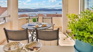 A balcony with a table and chairs, a potted plant, and a view of a lake and hills. - Apartment in Okrug Gornji with Seaview, Terrace, Air condition, WIFI (5051-2) (Okrug Gornji)