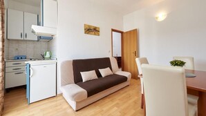 A compact living space with a kitchenette, a sofa, a dining table, and a small kitchen area. - Apartment in Seget Vranjica with Seaview, Balcony, Air condition, WIFI (5052-3) (Seget Vranjica)