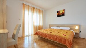 A hotel room with a bed, a chair, a nightstand with a lamp, and a window with curtains. - Apartment in Seget Vranjica with Seaview, Terrace, Air condition, WIFI (5052-5) (Seget Vranjica)