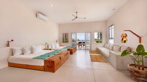 A modern hotel room with a large bed, a sofa, a dining area, and a view of the outdoors. - Topia Sunset Suite All Inclusive (El Pescadero)