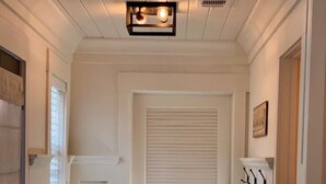 Un pasillo con una puerta blanca, una silla de madera y una pequeña mesa.