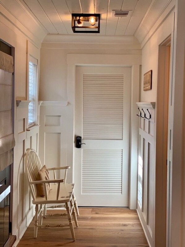 A hallway with a white door, a wooden chair, and a small table.