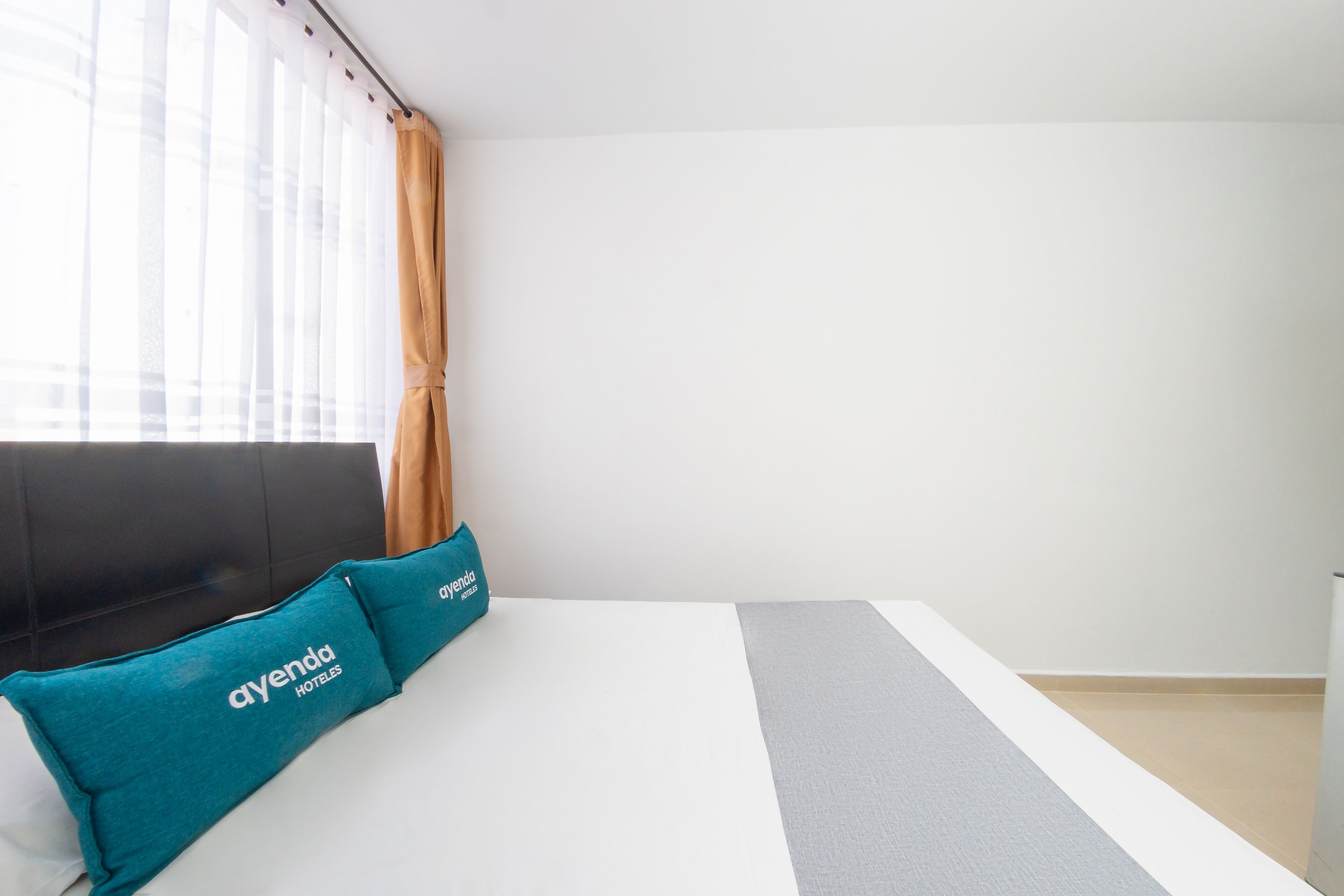 A hotel room with a bed, a window with curtains, and a pillow with the hotel name.