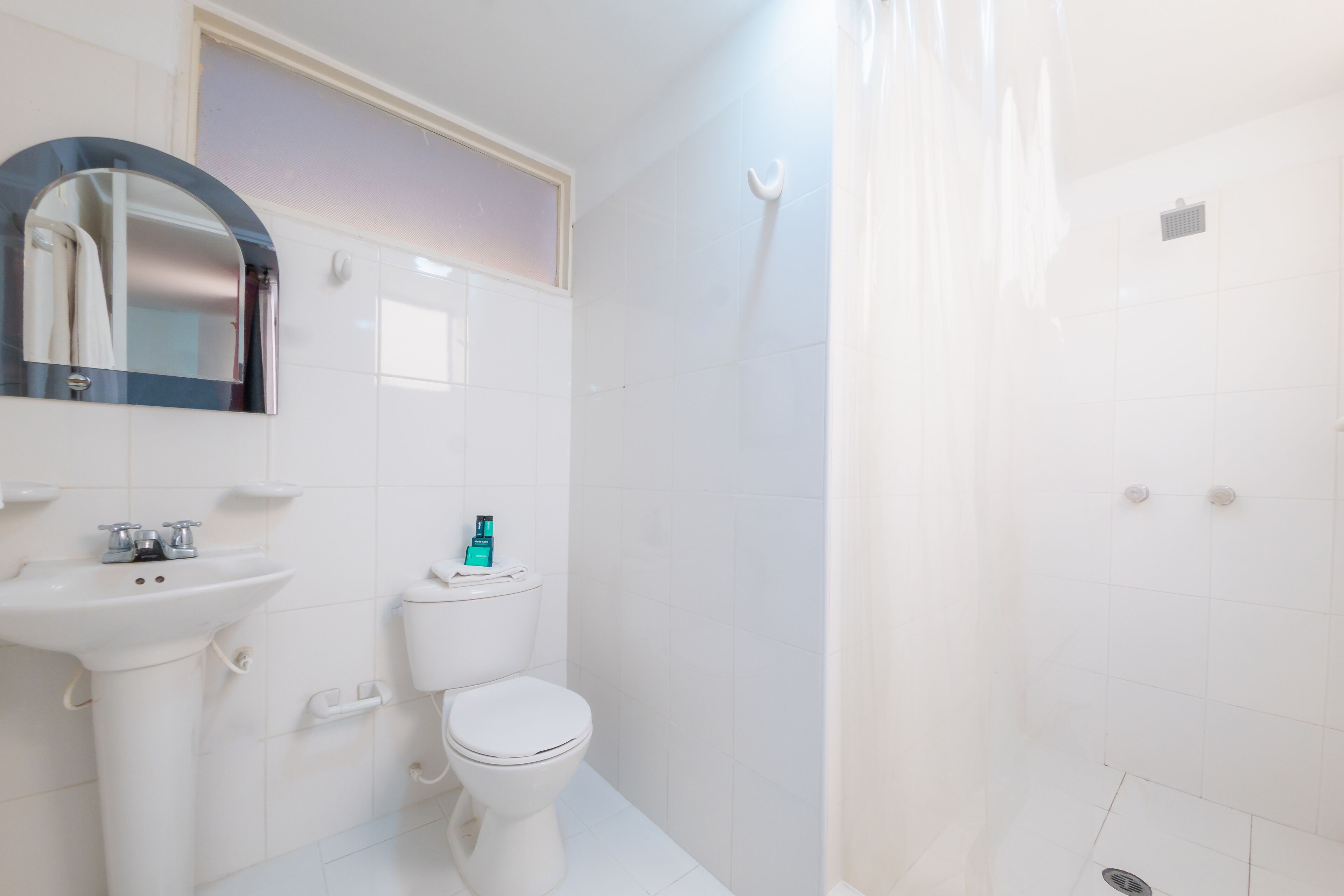 Et badeværelse med hvid vask, toilet og bruser.