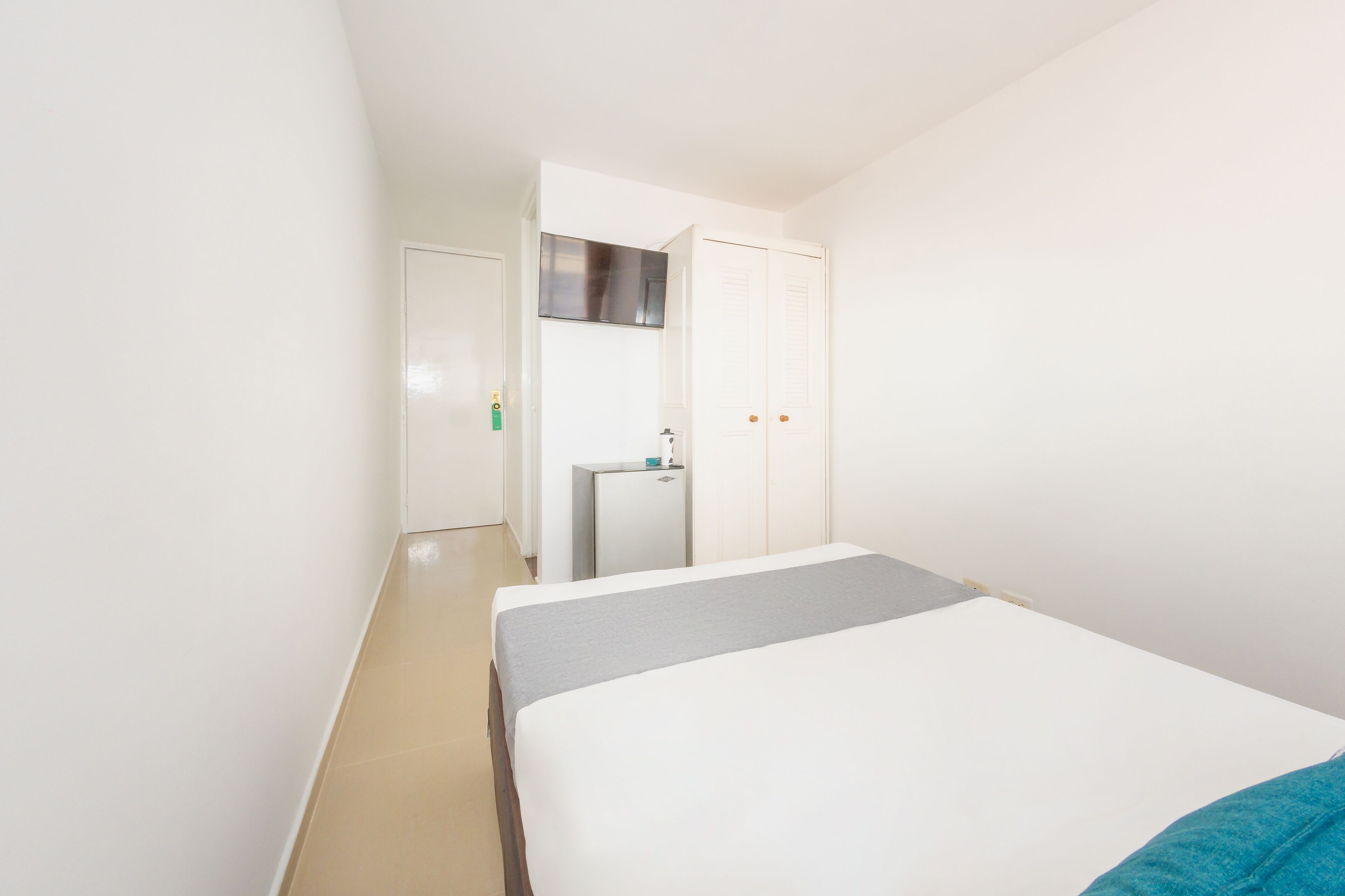 Une chambre avec un lit, un petit coin cuisine et une porte donnant sur une autre pièce.
