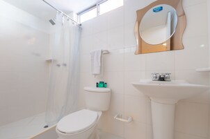A modern bathroom with a toilet, shower, and sink.