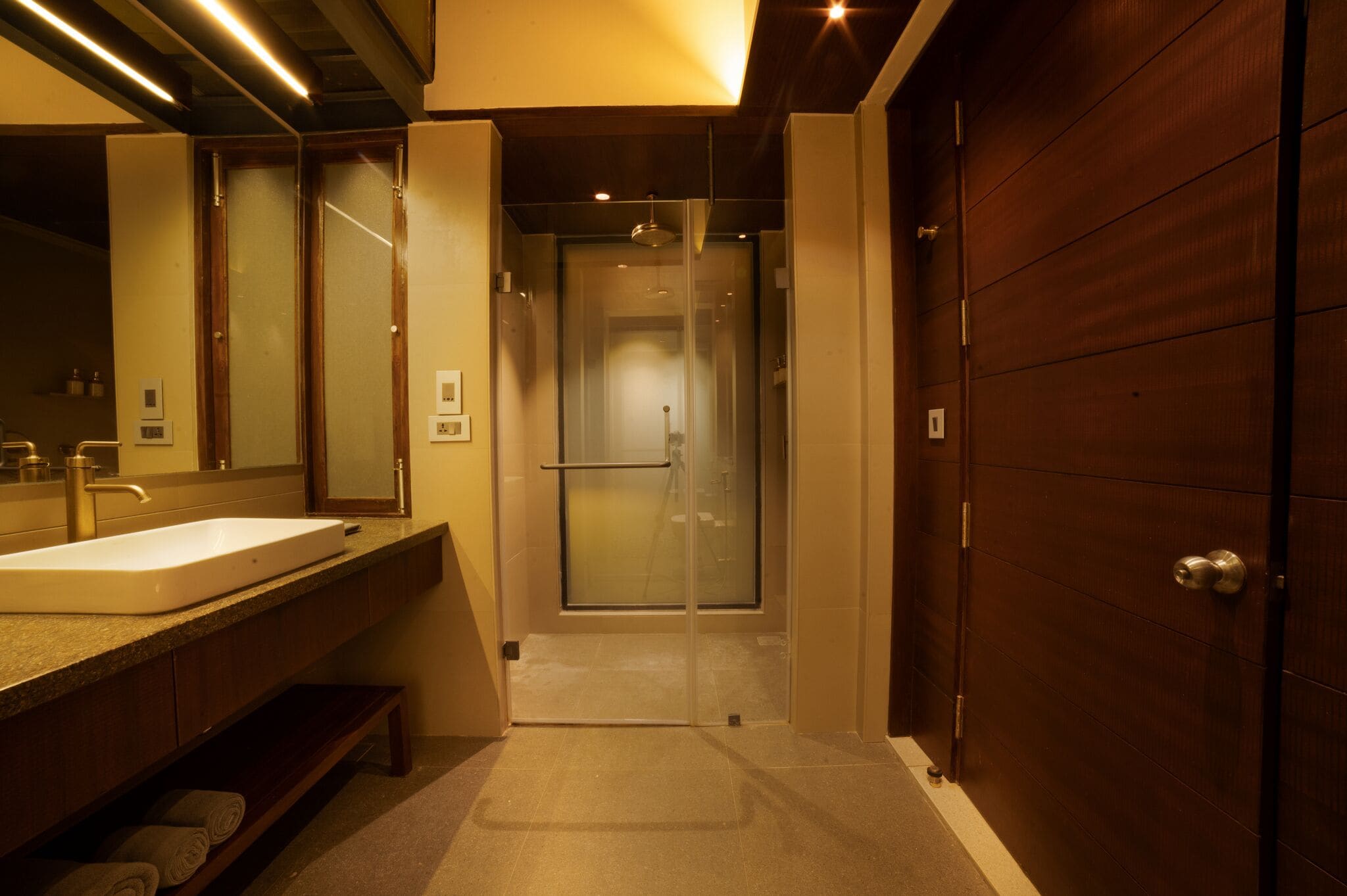 A modern bathroom with a large sink, mirror, and walk-in shower.