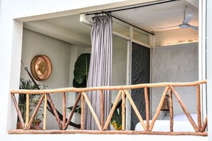 Een balkon met een houten hekwerk, een grijze gordijn en een plafondventilator.