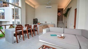 A modern living room with a sofa, dining table, and chairs. There is a kitchen area with a refrigerator and a sink. - Villa IV Casa Kuuts Ja (Casa de patos) (Xul-Ha)
