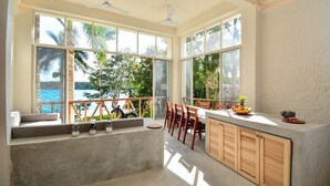 A kitchen with large windows, a dining area, and a view of the outdoors. - Villa IV Casa Kuuts Ja (Casa de patos) (Xul-Ha)