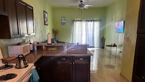 A kitchen with a central island, dark wooden cabinets, a white stove, and a ceiling fan. - Beachfront Paradise in Rolleville Steps to Sand, Pig Beach & Coco Plum (Exuma)