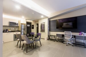 A modern kitchen with a microwave, refrigerator, and dining area with chairs and a table.