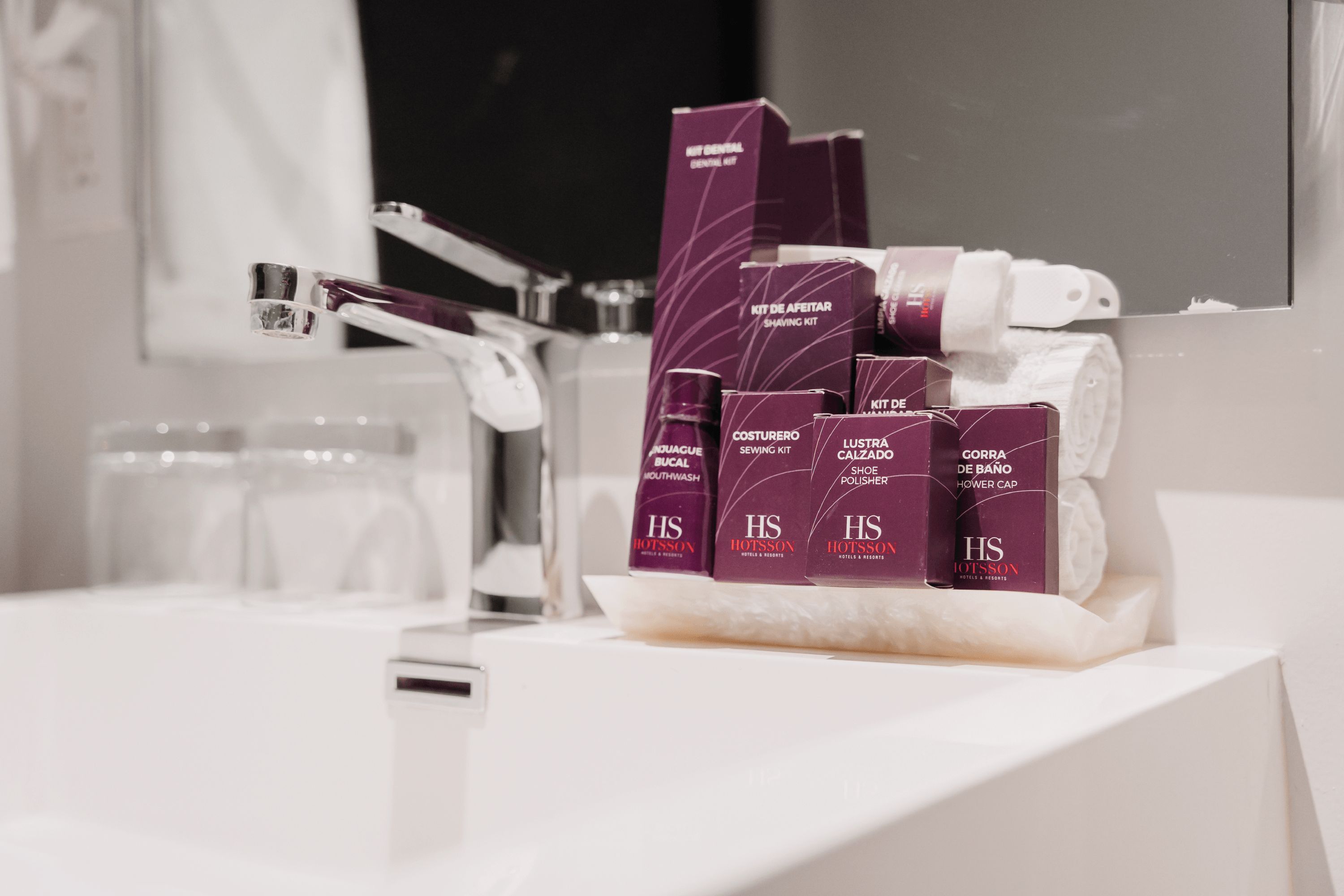 A bathroom with a white sink, a mirror, and a collection of personal care items including shaving kits and a toothbrush.