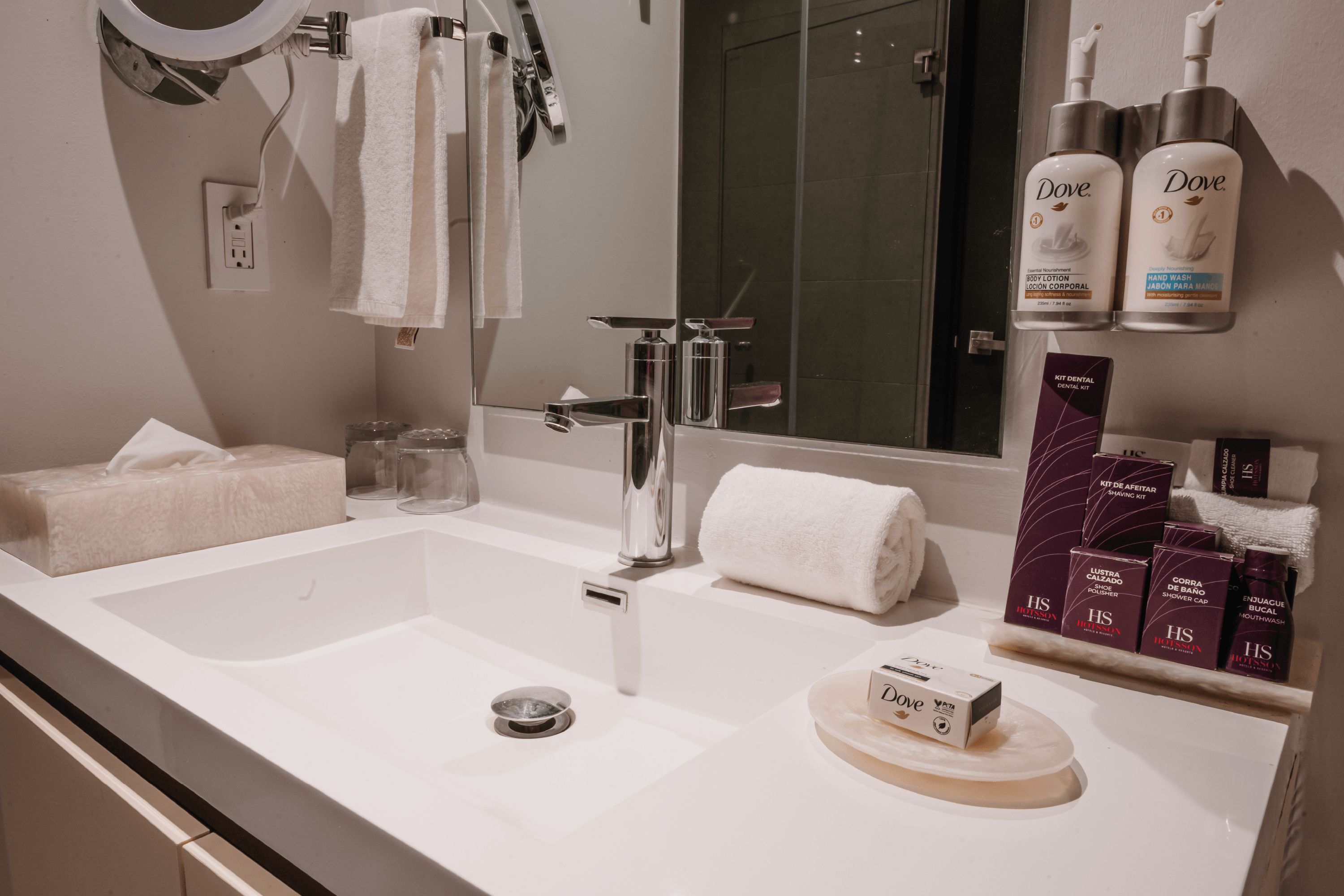 A modern bathroom with a large sink, a mirror, and various toiletries.