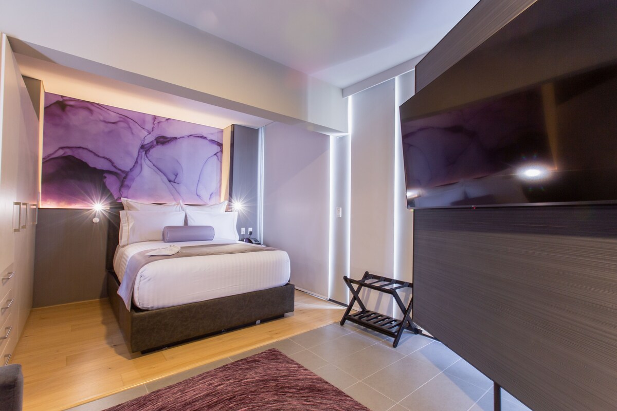 Une chambre à coucher moderne avec un lit, une télévision et un mur en marbre.