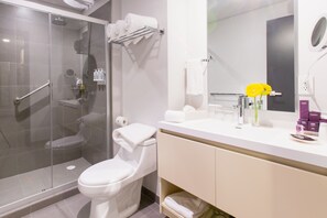 Une salle de bain moderne avec une douche à parois de verre, des toilettes, un meuble-lavabo avec un miroir et des articles de toilette.