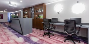 Un espace de bureau moderne comprenant un comptoir d’accueil, deux postes de travail équipés d’ordinateurs et un mur décoratif agrémenté d’étagères.