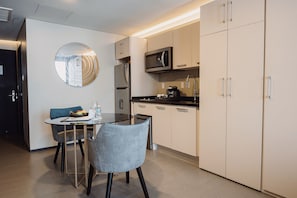 Una cocina moderna con comedor, que incluye un espejo redondo, electrodomésticos de acero inoxidable y muebles de cocina en tonos claros.