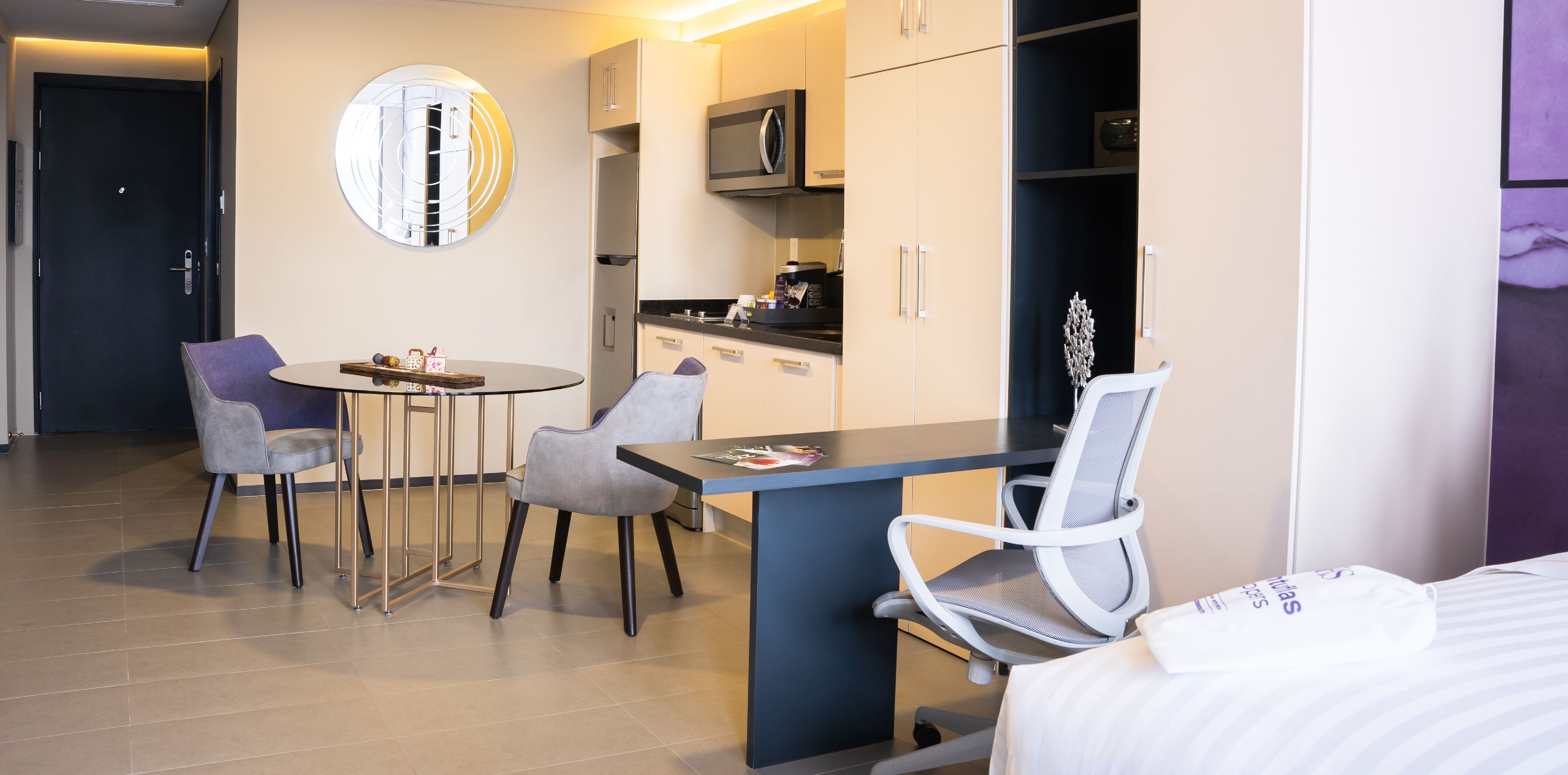 Ein modernes Hotelzimmer mit Essbereich, Küchenzeile und einem Bett.