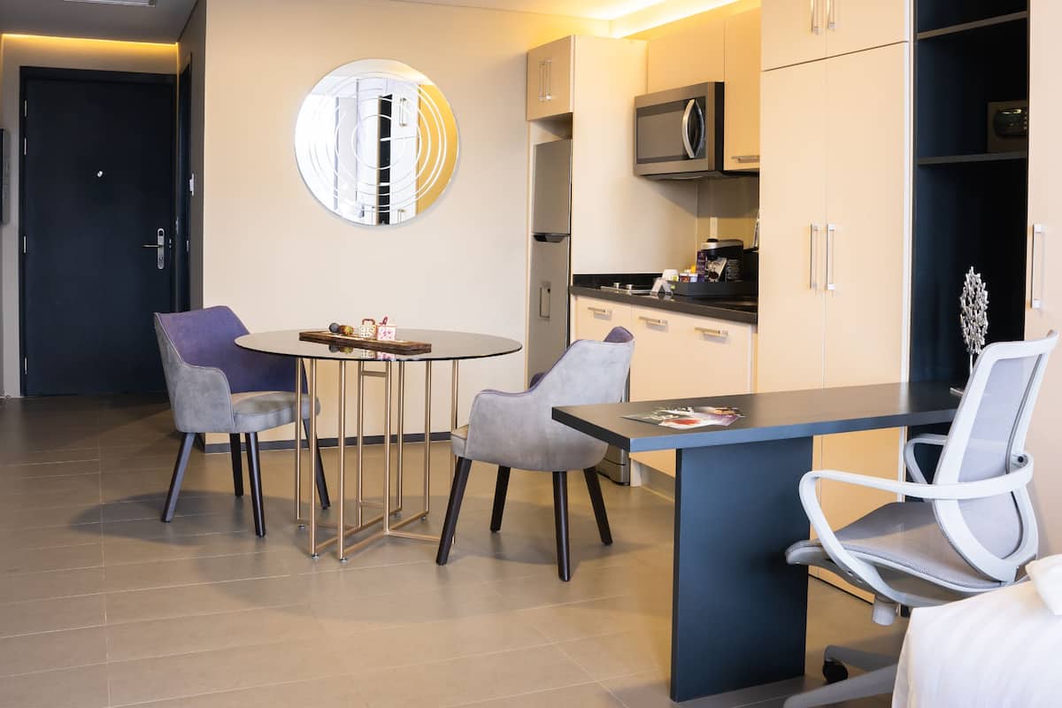 Une chambre d’hôtel moderne dotée d’un coin repas, d’une kitchenette et d’un lit.