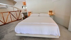 Een slaapkamer met een groot bed, een houten boktafel, een klein tafeltje met spiegel en twee wandlampen.