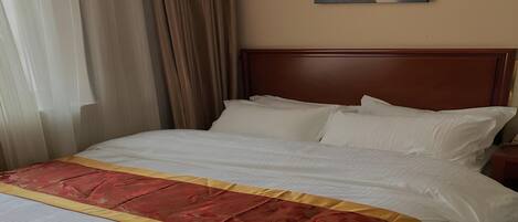 Quarto de hotel com uma cama grande, cabeceira de madeira e um quadro na parede.