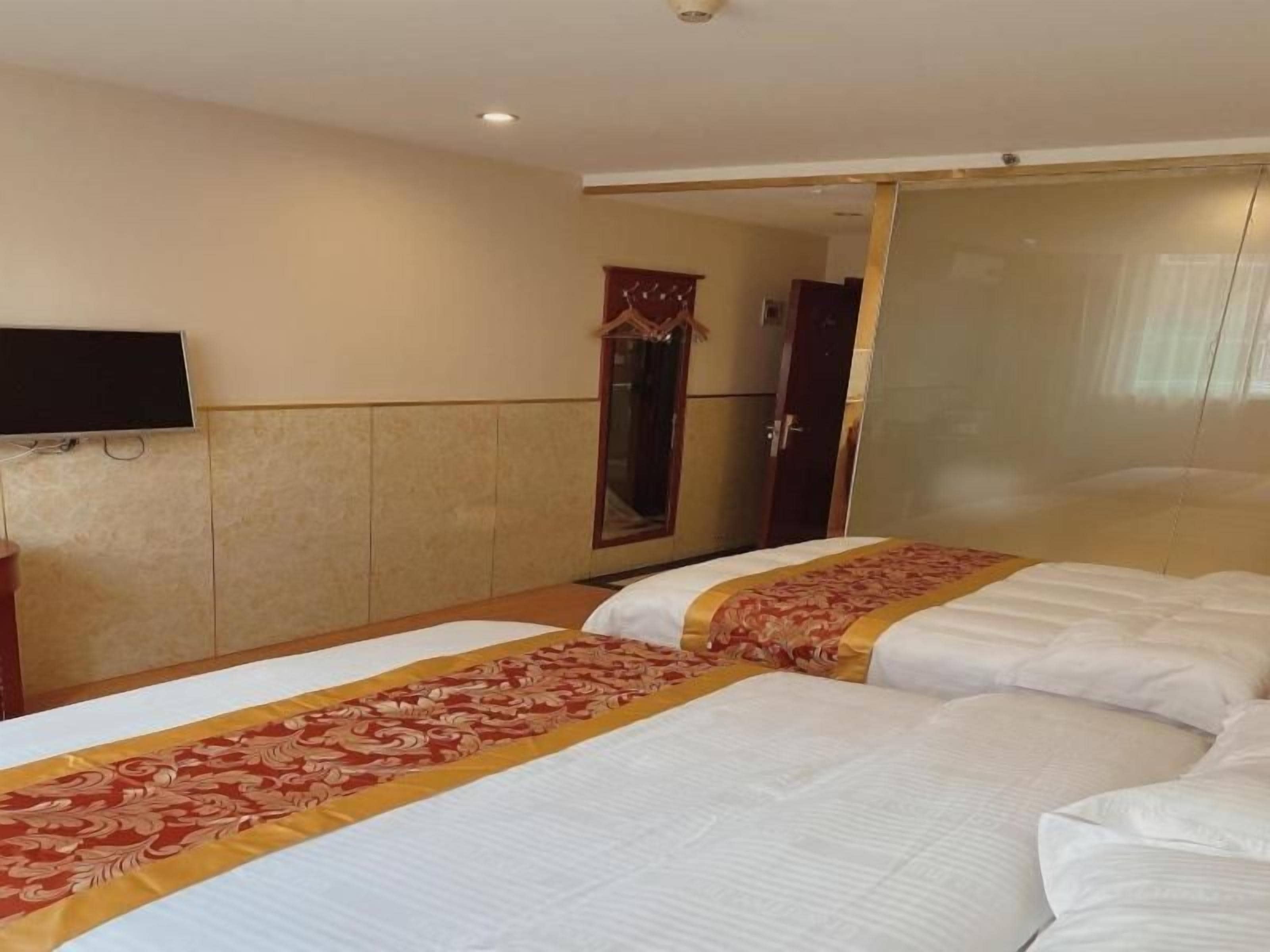 A hotel room with two beds, a television, and a mirror.