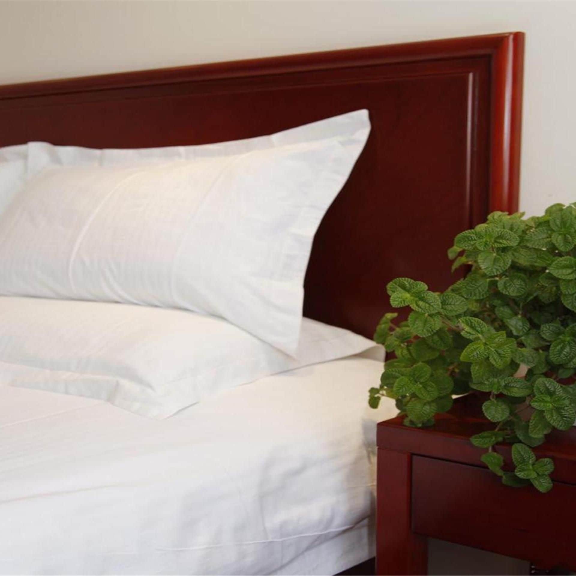 Una cama con ropa blanca y un cabecero de madera.