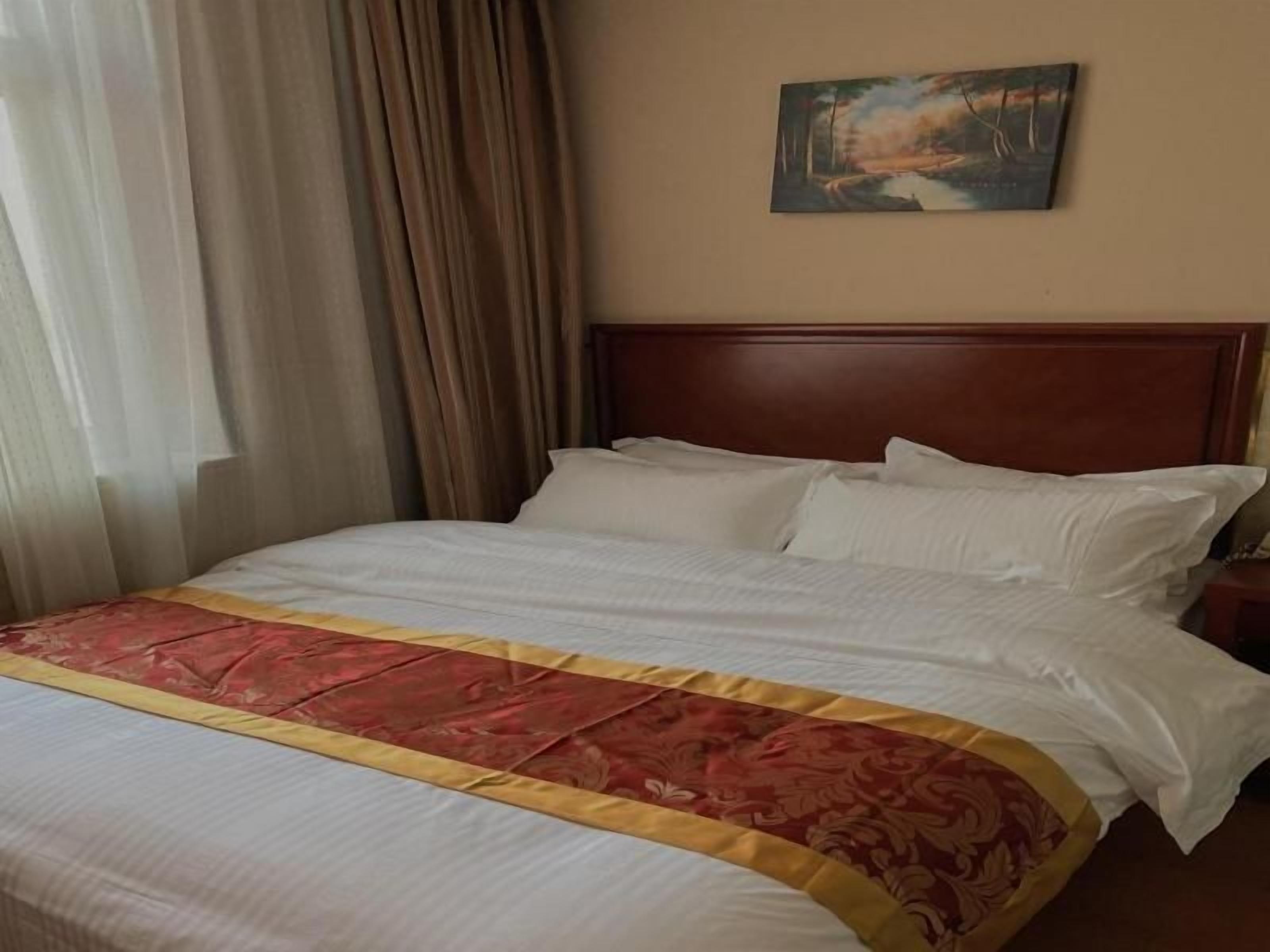 A hotel room with a large bed, a wooden headboard, and a painting on the wall.