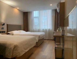 Ein Hotelzimmer mit zwei Betten, einem kleinen Tisch und einem Spiegel.