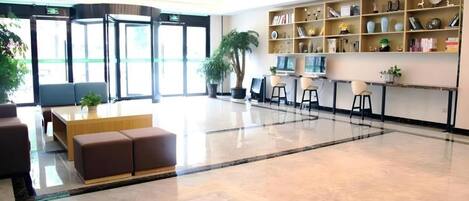 A spacious lobby with a seating area, a reception desk, and a large window.