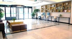 Eine geräumige Lobby mit einer Rezeption, einer Sitzecke und einem großen Fenster.