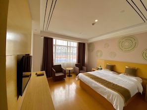 A hotel room with a bed, a desk, a chair, a small table, and a window with curtains. - Greentree Inn Shanghai Fengxian District Xiaotang Road Hotel (Shanghai)