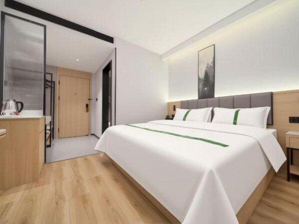 Une chambre d’hôtel moderne avec un grand lit, une table de chevet et une vue sur le couloir.
