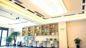 A reception area with a bookshelf, a plant, and a desk with a computer.
