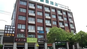 A multi-story hotel with a modern design, featuring a prominent logo at the top.