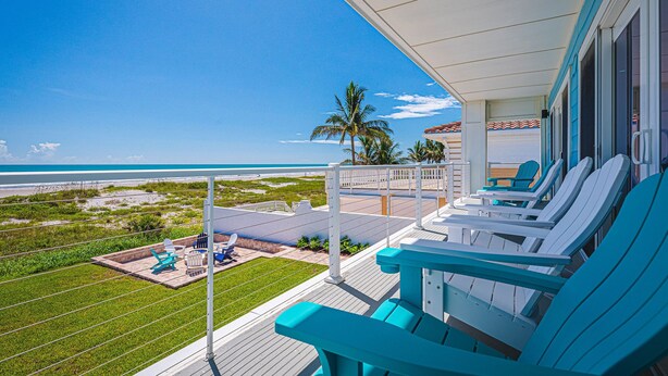 Een balkon met turquoise stoelen met uitzicht op een strand.