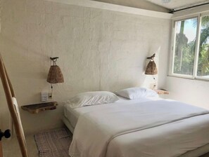 Una camera da letto con un letto, due lampade a parete, uno scaffale in legno e una finestra vista verde.