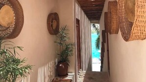 Um corredor com tapeçarias nas paredes, um vaso de planta e vista para uma praia.