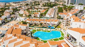 A residential area with a large swimming pool surrounded by white buildings with orange roofs.
